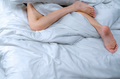 Woman barefoot on bed over white linen blanket and bed sheet in hotel or home bedroom. Sleep - PhotoDune Item for Sale