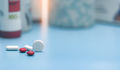 Round white tablets and blurred red and white tablets pills. Pills on blurred pills plastic bottle. - PhotoDune Item for Sale