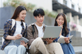 Young Asian woman college student with friends at outdoors. College student working on the college - PhotoDune Item for Sale