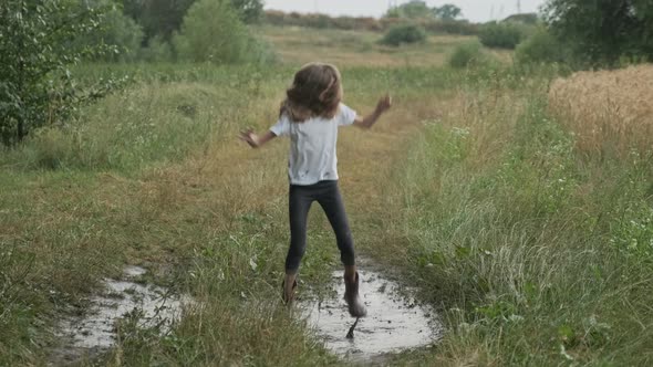 Beautiful Smiling Girl Jumping in Very Muddy Puddle