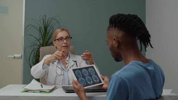 Female Doctor Using Tablet Explaining MRI Diagnosis to Patient Indoors