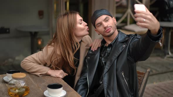 Positive Gay Man and Young Woman Taking Selfie Making Faces Gesturing Kiss Showing Tongue Smiling