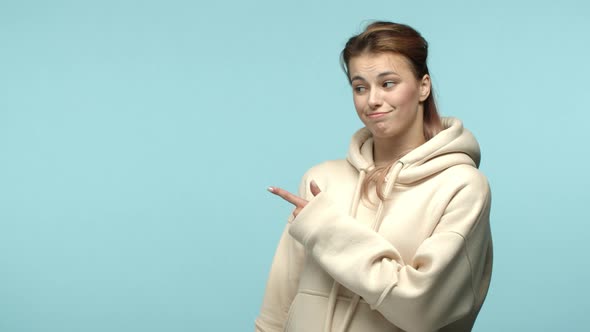 Slow Motion of Pretty Blond Girl in White Hoodie Pointing Left at Copy Space Then Showing Thumbs Up