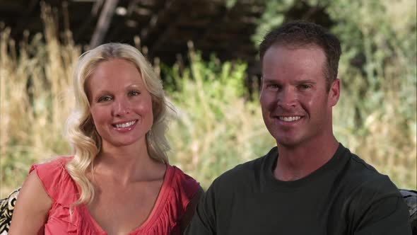 Slow handheld shot of two beautiful people smiling and looking at the camera