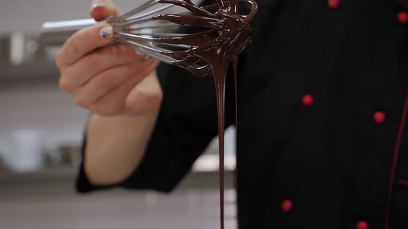 Close-up of a Pastry Chef Mixing Liquid Chocolate with a Whisk in the Kitchen.