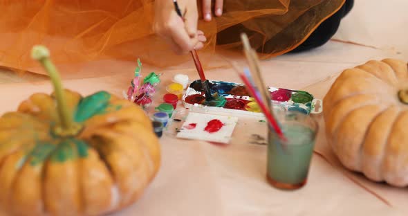 Happy child decorating a pumpkin at home Little girl drawing face