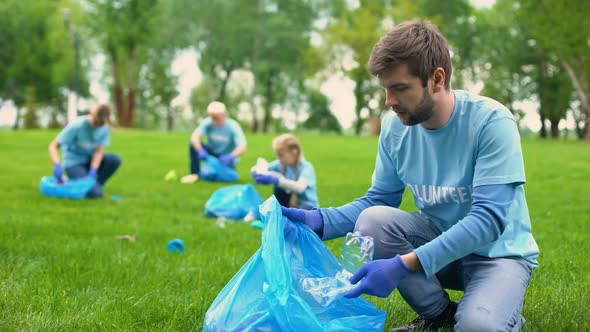 Happy Male Volunteer Putting Rubbish in Garbage Bag and Smiling Responsibility