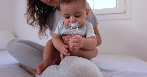 Young loving mother holding her baby on bed at home