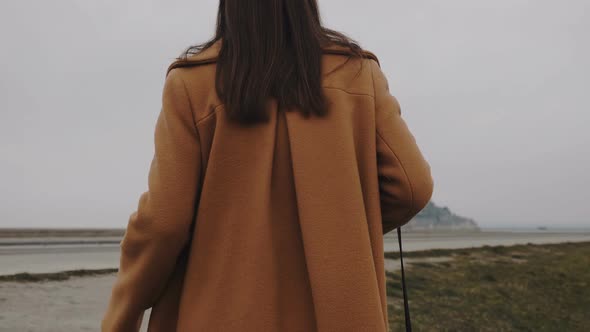 Back View Beautiful Blogger Woman Walking Uphill To Amazing Misty Mont Saint Michel Castle on