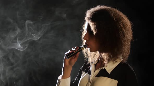 Girl Smokes a Vape, She Enjoys a Delicious Aroma. Black Background