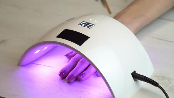 Girl Placed Hand Under an Nail Polish Curing Lamp and Waits for the Nail Polish to Harden