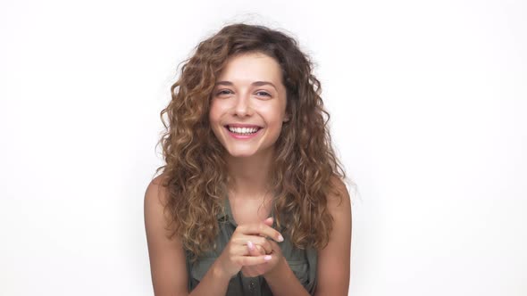 Young Pretty Lady with Long Curly Hair Smiling Being Shy on Camera Over White Background