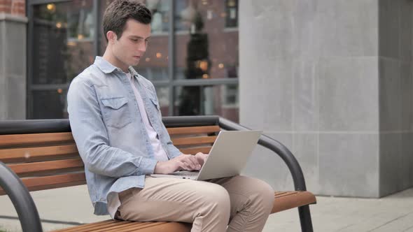 Sitting Outdoor Young Man with Headache Using Laptop