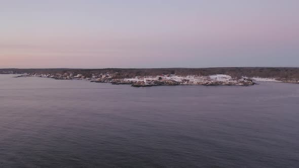 Portland Head Light blinking during winter sunrise AERIAL PUSH IN