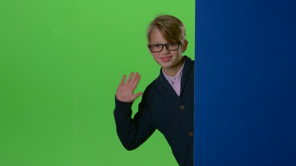Happy Child Boy in Glasses Peeps Out From the Wall on a Green Screen