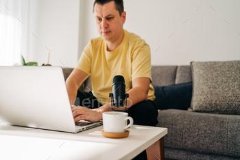 IT freelancer men with microphone typing in laptop working from home office. Programmers sitting on