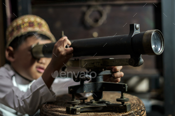 Smart school Asian boy studying old brass theodolite at the Aceh Pedir Museum