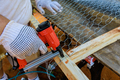 A worker nails metal mesh to a wooden frame with the help of a nail gun - PhotoDune Item for Sale