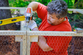 Worker uses screwdriver to wooden domestic chicken coop on farm that contains metal grid for - PhotoDune Item for Sale