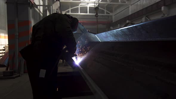 Manual Metal Welding, Spark Flow on Dark Background. Industrial Production. Protective Masked Welder