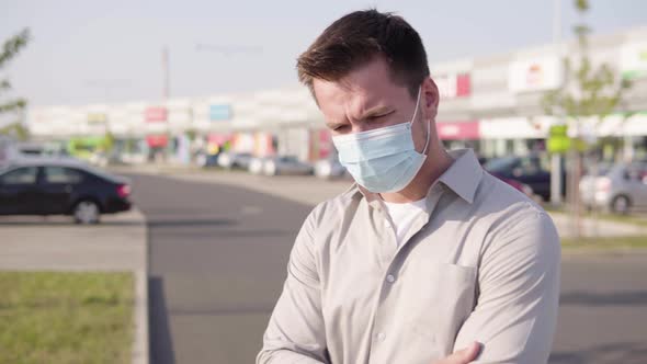 A Young Caucasian Man in a Face Mask Acts Frustrated in an Urban Area