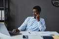 Young black businessman using laptop sitting at desk in office and - PhotoDune Item for Sale