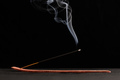 Smoke curls of burning incense stick in wooden holder for relaxation and meditation black background - PhotoDune Item for Sale