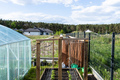 A wooden crate with cucumbers and strings hanging from a scaffold, standing on the grass. - PhotoDune Item for Sale