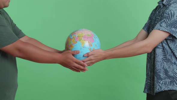 Man Hand In The World Globe To Another Man While Standing In Front Of Green Screen Background