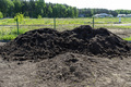 A heap of pure black earth lying in the yard next to the fence. - PhotoDune Item for Sale