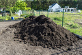 A heap of pure black earth lying in the yard next to the fence. - PhotoDune Item for Sale