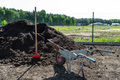 A heap of pure black earth lying in the yard next to the fence, visible shovel and full wheelbarrow. - PhotoDune Item for Sale
