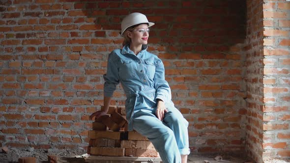 Female Architect or Bricklayer Sitting on a Pile of Bricks on a Construction Site