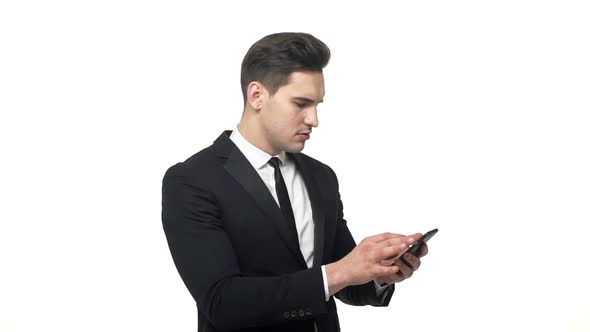 Young Hadnsome Businessman Typing on Mobile with Serious Facial Expression Isolated Over White