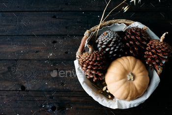 o basket next to a yellow pumpkin on a wooden table seen from a zenithal view.
