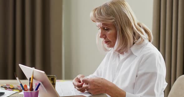 Elderly Businesswoman with Migraine Taking Pill