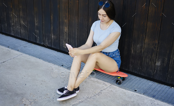 Millennial hipster girl resting on penny board and chatting
