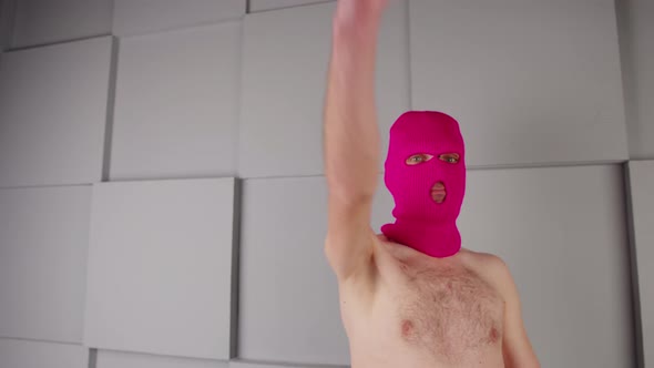 Unrecognizable Person in Pink Balaclava with a Bare Torso Makes Imaginary Gun Out of Hands and Makes
