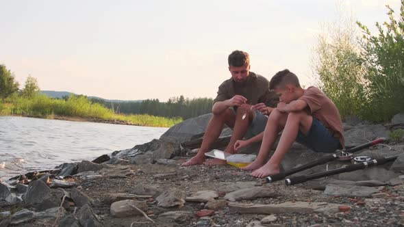 Son and Father Sitting on Lake Shore