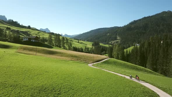 Three people cycling in landscape, Alta Badia, Italy