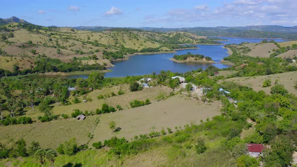 Aerial forward over green fields surrounding Bao dam in Dominican Republic