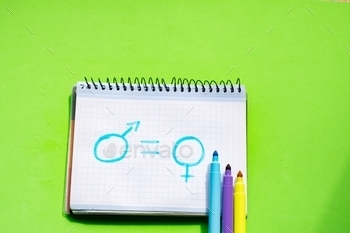 Drawing about gender equality on a white page of the notebook on green desk