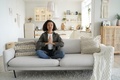 Mixed race girl practices yoga, meditation at home sitting in lotus pose on couch. Healthy lifestyle - PhotoDune Item for Sale