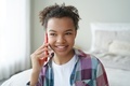 Smiling mixed race teen girl answers phone call, enjoying talk with friend in bedroom at home - PhotoDune Item for Sale