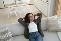 Happy african american young girl relaxing on comfortable couch in cozy living room, enjoying break - PhotoDune Item for Sale