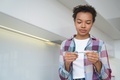Unhealthy mixed race teen girl check body temperature with digital thermometer, standing at home - PhotoDune Item for Sale