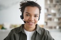 Smiling mixed race girl student in headset, looking at camera. Distance education, elearning - PhotoDune Item for Sale