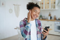 Modern young mixed race girl listening to music, holding smartphone, using musical apps at home - PhotoDune Item for Sale