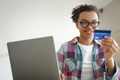 Mixed race teen girl holds credit card, using online banking services at laptop at home. E commerce - PhotoDune Item for Sale