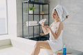 Female holding bottle of natural skincare cosmetics, moisturizing body after taking bath in bathroom - PhotoDune Item for Sale